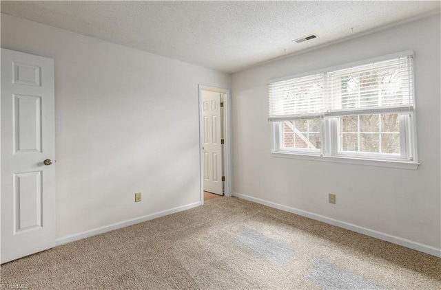 carpeted spare room with a textured ceiling, visible vents, and baseboards