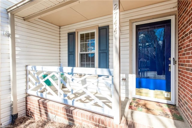 property entrance featuring covered porch and brick siding