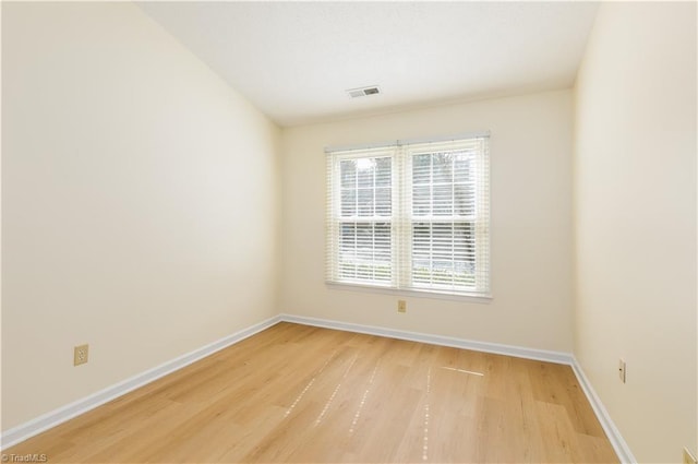 unfurnished room featuring light wood-style flooring, visible vents, and baseboards