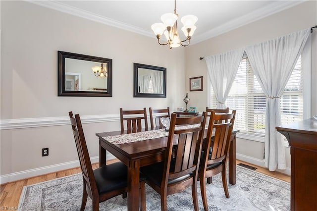 dining area with wood-type flooring, ornamental molding, and an inviting chandelier