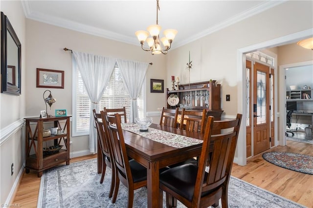 dining room with an inviting chandelier, crown molding, light hardwood / wood-style floors, and french doors