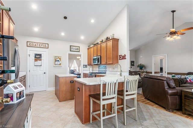 kitchen featuring appliances with stainless steel finishes, a center island, sink, kitchen peninsula, and ceiling fan