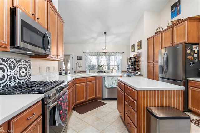 kitchen featuring kitchen peninsula, appliances with stainless steel finishes, hanging light fixtures, a kitchen island, and sink