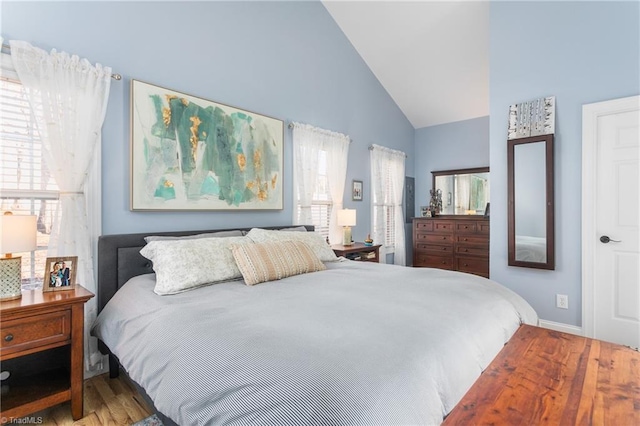 bedroom featuring high vaulted ceiling, multiple windows, and hardwood / wood-style floors