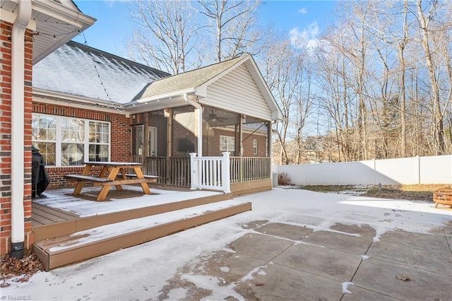 snow covered patio with ceiling fan and a sunroom