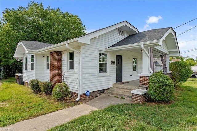 view of front of house featuring a porch, a shingled roof, and a front lawn