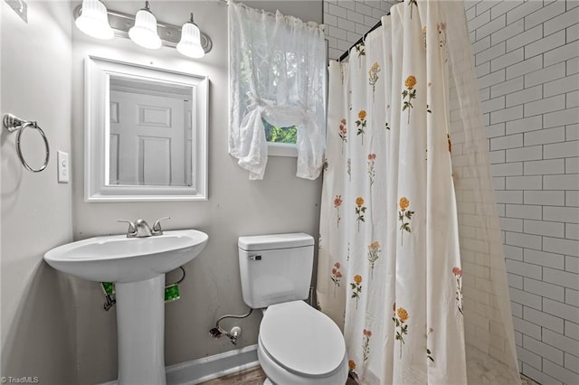 full bathroom featuring toilet, a sink, and tiled shower