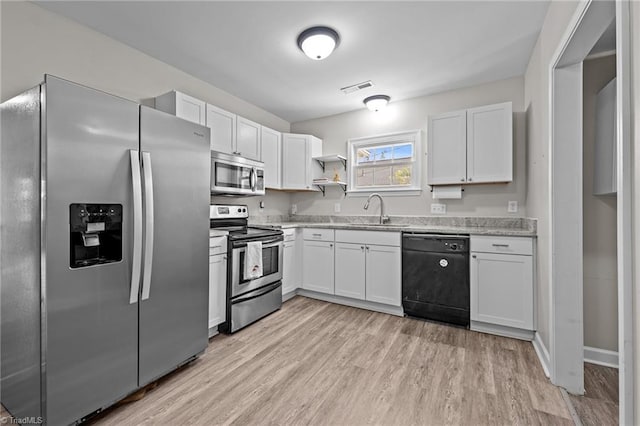 kitchen with white cabinets, appliances with stainless steel finishes, a sink, light wood-type flooring, and visible vents