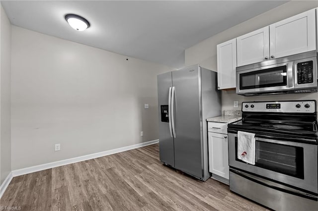 kitchen featuring baseboards, light wood-style flooring, white cabinetry, and stainless steel appliances