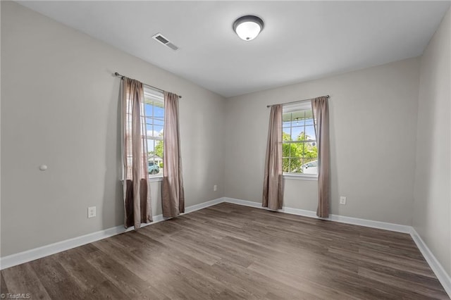 spare room featuring visible vents, baseboards, and dark wood-style floors