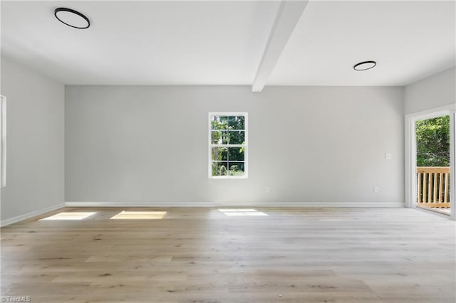 spare room with light wood-style floors, baseboards, and beamed ceiling