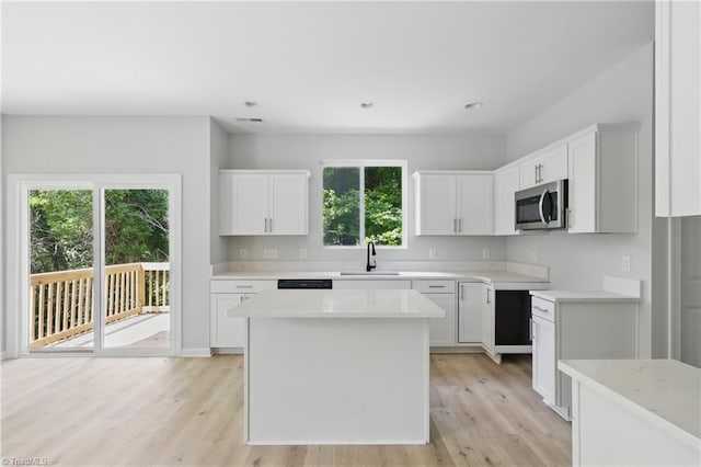 kitchen with stainless steel microwave, a sink, light wood-style flooring, light countertops, and recessed lighting