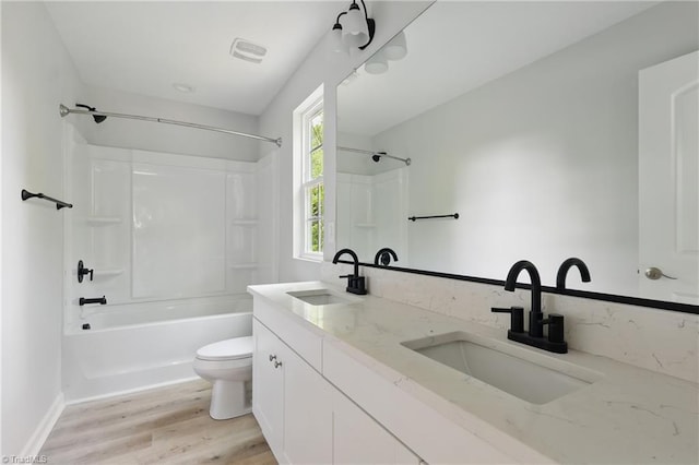 bathroom with toilet, wood finished floors, shower / bath combination, double vanity, and baseboards