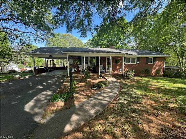 ranch-style house featuring brick siding, driveway, an attached carport, a front lawn, and a chimney