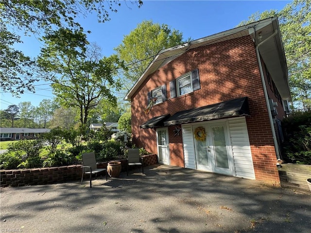 view of front of property with a patio, french doors, and brick siding