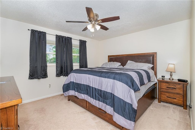 bedroom with ceiling fan, a textured ceiling, and light colored carpet