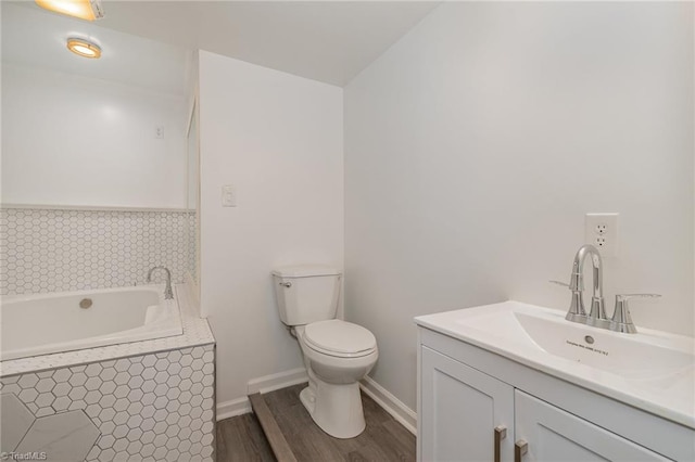 bathroom featuring tiled tub, wood-type flooring, vanity, and toilet