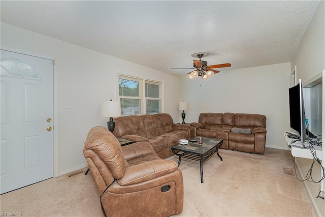 living room with ceiling fan, a textured ceiling, and light carpet