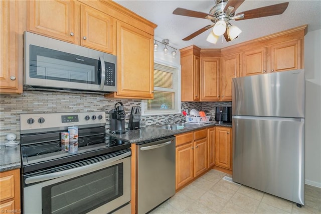 kitchen with light tile patterned floors, stainless steel appliances, backsplash, ceiling fan, and sink