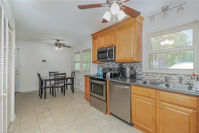 kitchen featuring ceiling fan, appliances with stainless steel finishes, light tile patterned flooring, and backsplash