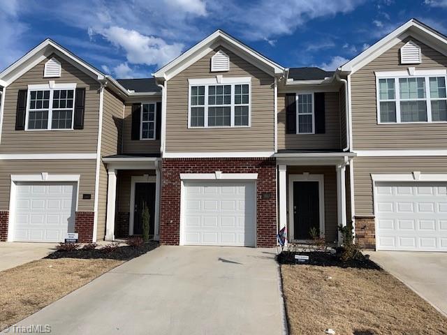 townhome / multi-family property featuring concrete driveway, brick siding, and an attached garage