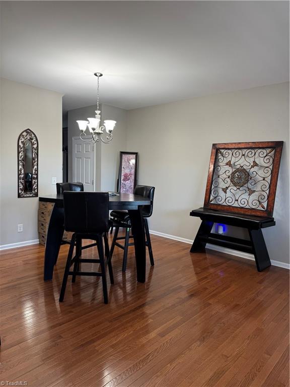 dining area with baseboards, a chandelier, and wood finished floors