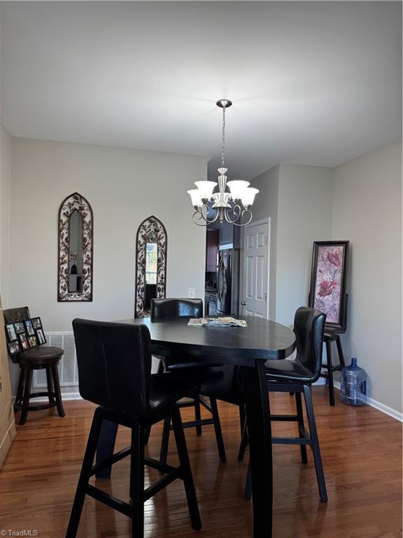 dining room featuring a notable chandelier, dark wood finished floors, visible vents, and baseboards