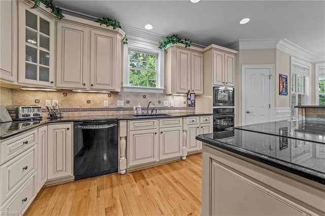 kitchen with black appliances, a sink, light wood-style flooring, crown molding, and dark stone counters