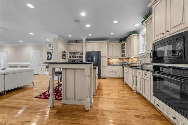 kitchen with black appliances, ornamental molding, dark countertops, a sink, and backsplash