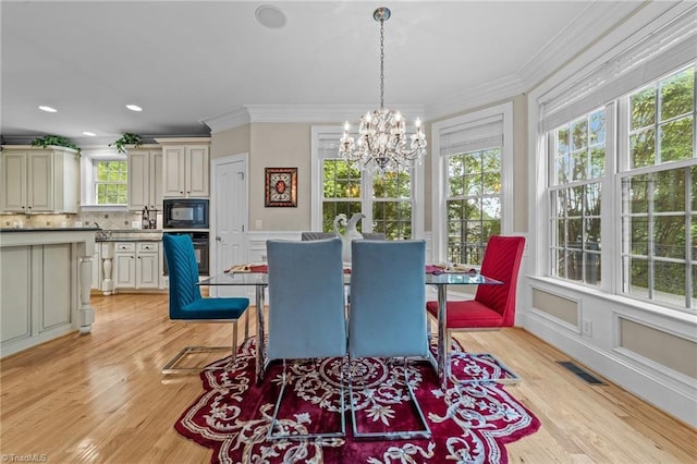 dining area featuring a chandelier, light wood finished floors, and crown molding