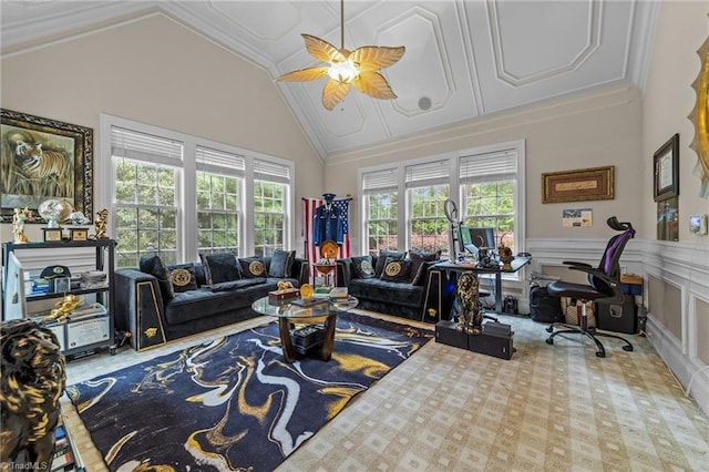 carpeted living area featuring healthy amount of natural light, ceiling fan, a wainscoted wall, high vaulted ceiling, and a decorative wall