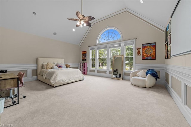 bedroom featuring carpet floors, a wainscoted wall, a decorative wall, high vaulted ceiling, and ceiling fan