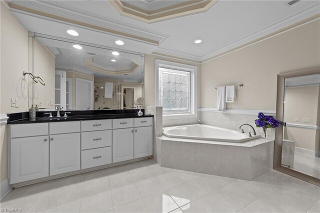 bathroom featuring a raised ceiling, ornamental molding, a garden tub, double vanity, and tile patterned floors