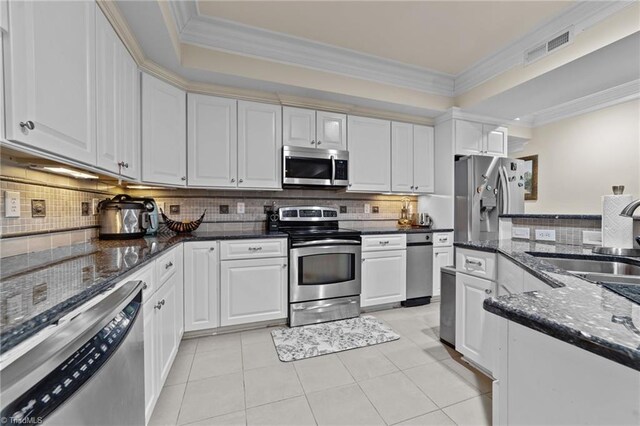 kitchen featuring stainless steel appliances, a sink, light tile patterned floors, white cabinets, and decorative backsplash