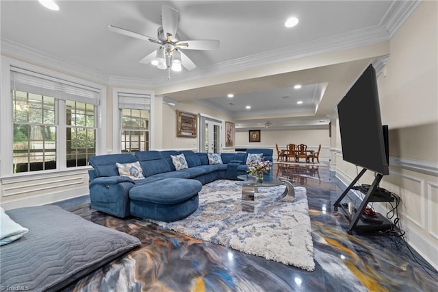 living area with a ceiling fan, crown molding, a decorative wall, and a wainscoted wall
