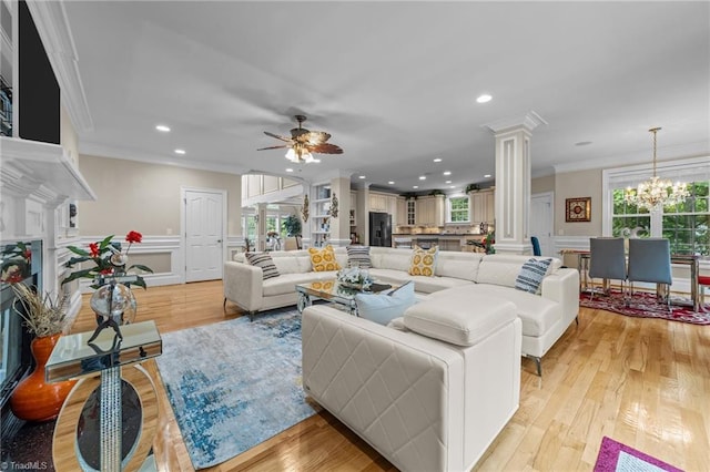 living room featuring decorative columns, ornamental molding, a decorative wall, light wood-style floors, and a ceiling fan