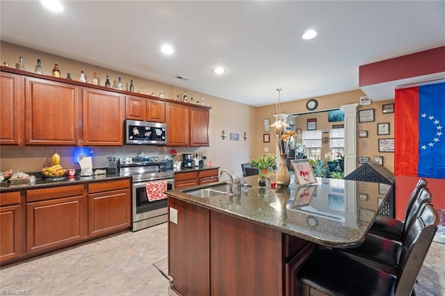 kitchen featuring ornate columns, a breakfast bar, pendant lighting, sink, and stainless steel appliances