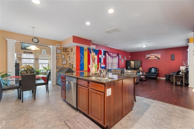 kitchen with ornate columns, pendant lighting, an island with sink, dishwasher, and sink