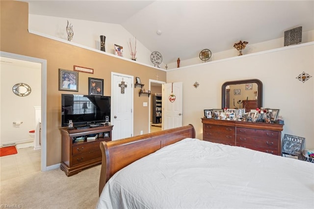 bedroom with light carpet, ensuite bath, and vaulted ceiling