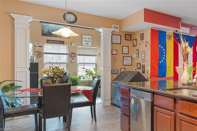 kitchen with sink, ornate columns, dark stone countertops, stainless steel dishwasher, and pendant lighting