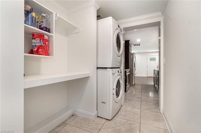 clothes washing area featuring baseboards, stacked washing maching and dryer, and visible vents