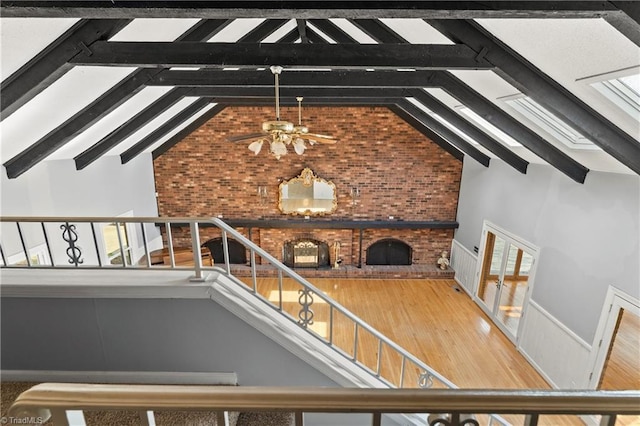 interior space featuring ceiling fan, a fireplace, beamed ceiling, and wood-type flooring