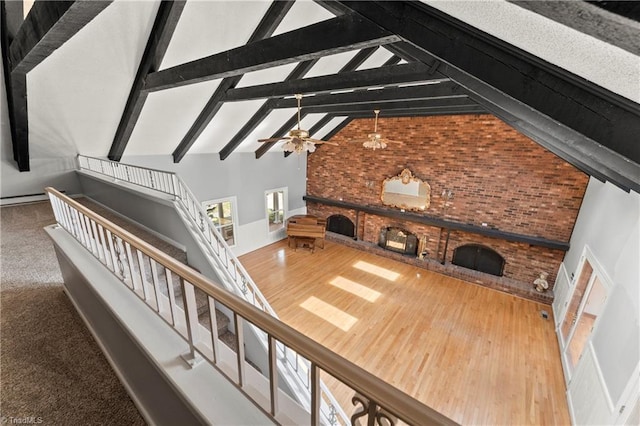 living room with beamed ceiling, high vaulted ceiling, ceiling fan, and brick wall