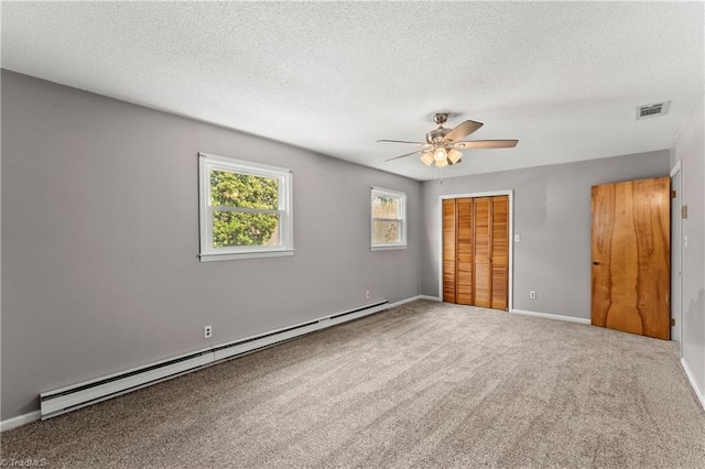 unfurnished bedroom with carpet flooring, a textured ceiling, ceiling fan, a baseboard radiator, and a closet