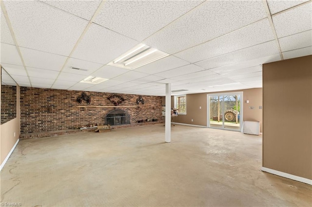 basement with a brick fireplace, a drop ceiling, and brick wall