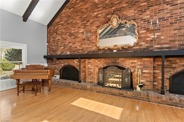 unfurnished living room with beam ceiling, a fireplace, high vaulted ceiling, and wood-type flooring