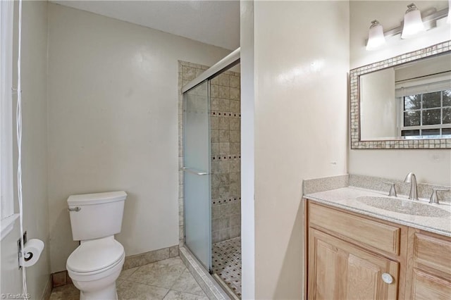 bathroom featuring tile patterned floors, vanity, toilet, and a shower with shower door