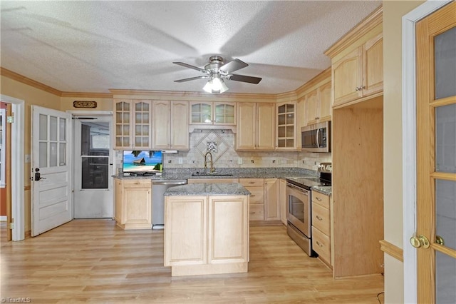 kitchen featuring light brown cabinetry, stainless steel appliances, a kitchen island, and sink