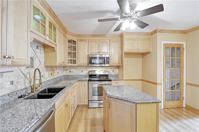 kitchen featuring decorative backsplash, light stone counters, stainless steel appliances, sink, and light brown cabinets