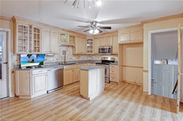 kitchen with appliances with stainless steel finishes, light wood-type flooring, light brown cabinetry, sink, and a center island